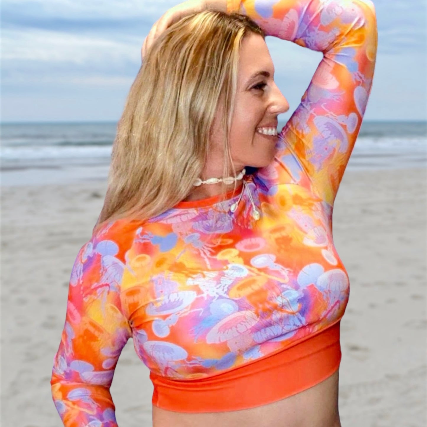 Pacific sea nettle jellyfish with shades of red, orange pink and purple on a cropped rashguard made with recycled fabric.