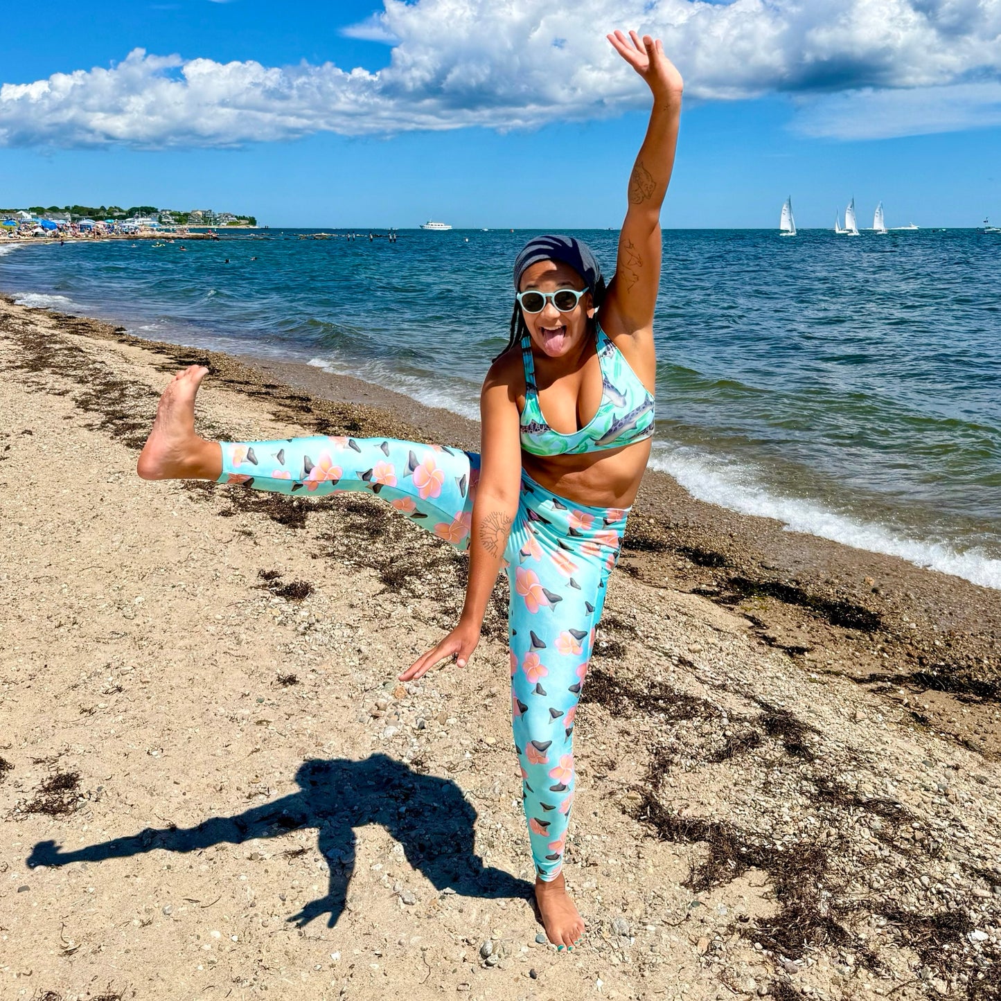 A teal and mint swirly background with Bull shark teeth and pinky orange plumeria flowers on our Shark Tooth Paradise Recycled Dive Leggings with pockets