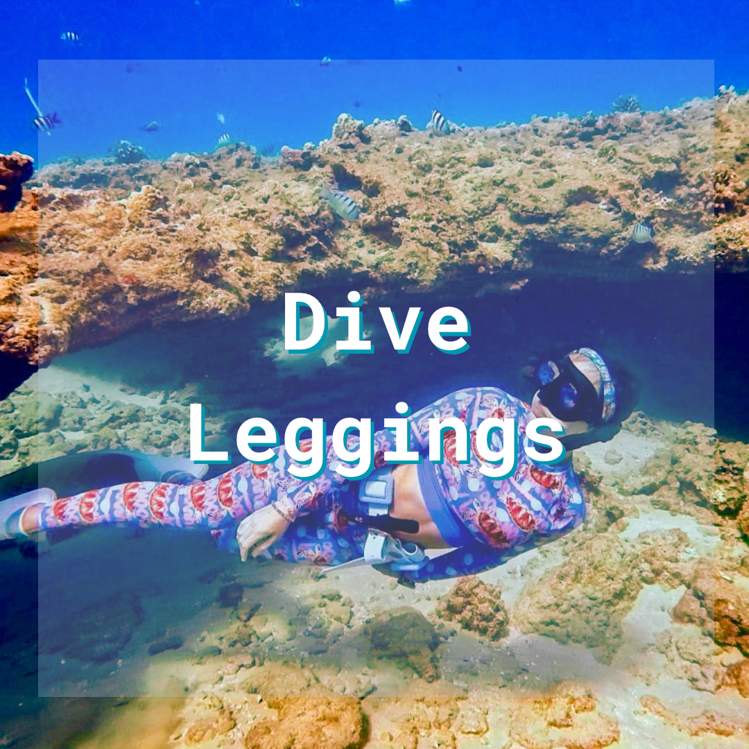 A woman free diving underwater with fish and coral, wearing leggings and a cropped rashguard. Text on the image says “dive leggings” to indicate the items in the collection. 