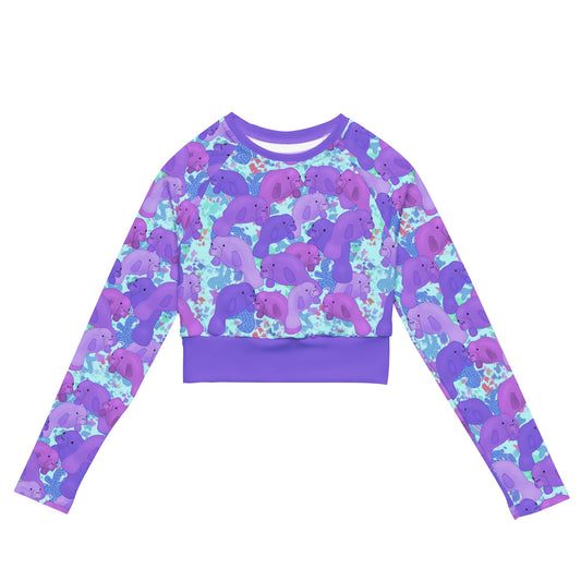 Purple manatees on a blue background of a cropped sustainable rashguard 