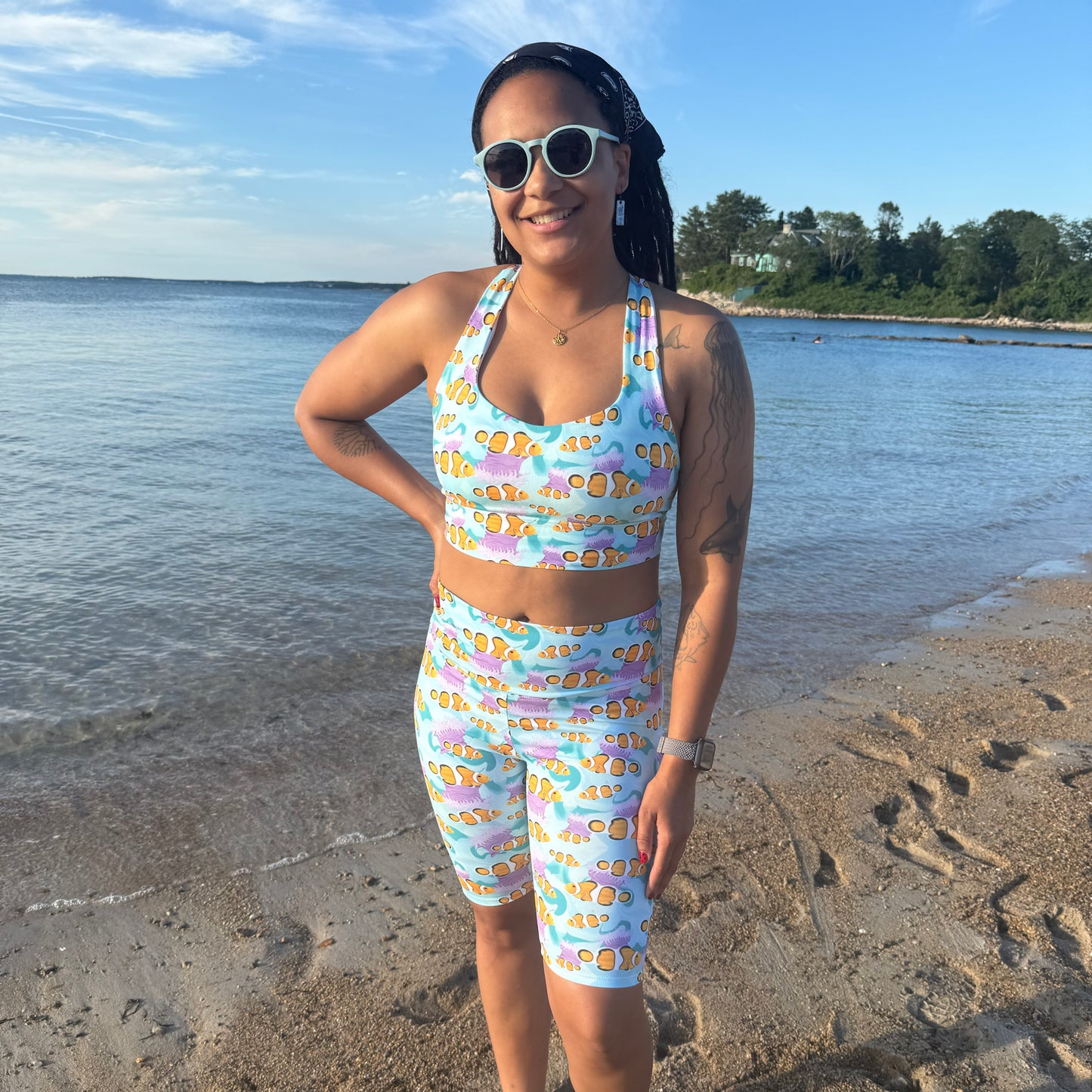 woman standing on a beach wearing blue clownfish bike shorts and sports bra 