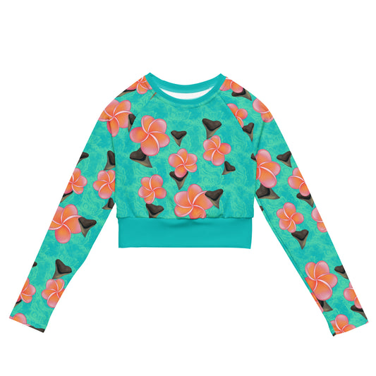 A teal and mint swirly background with Bull shark teeth and pinky orange plumeria flowers on our Shark Tooth Paradise Recycled Cropped Long Sleeve Rashguard