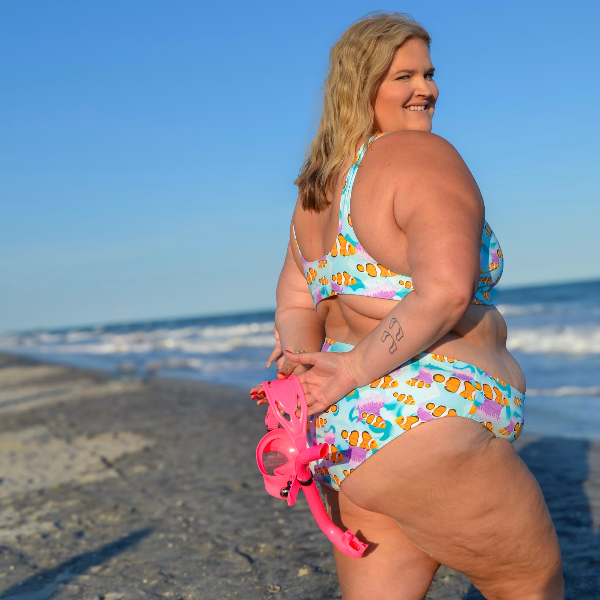 Woman standing on the beach wearing a blue, pink and orange clownfish bikini
