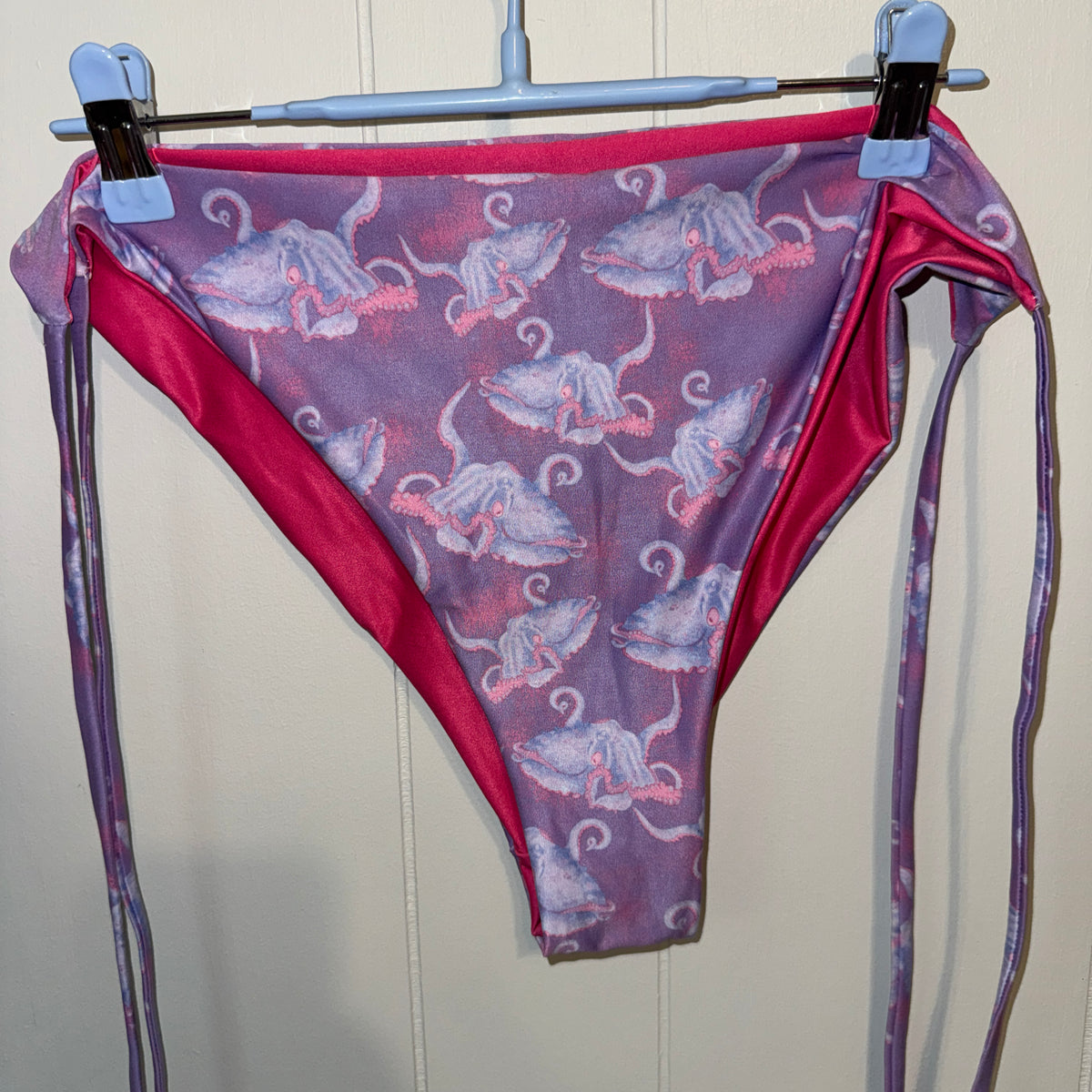 Purple and pink octopus string bikini bottom on a hanger 
