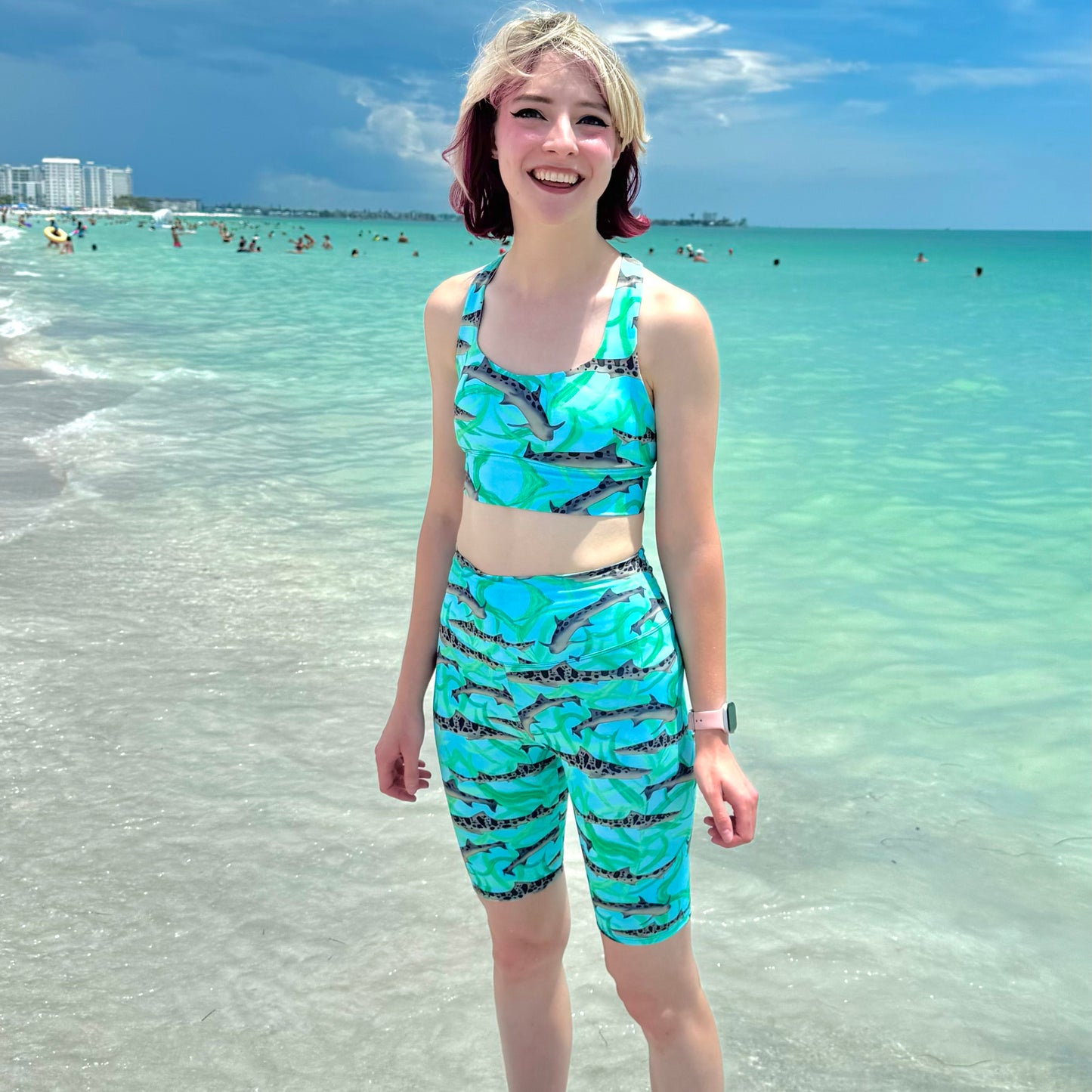 woman on the beach wearing blue leopard shark sports bra and bike shorts 