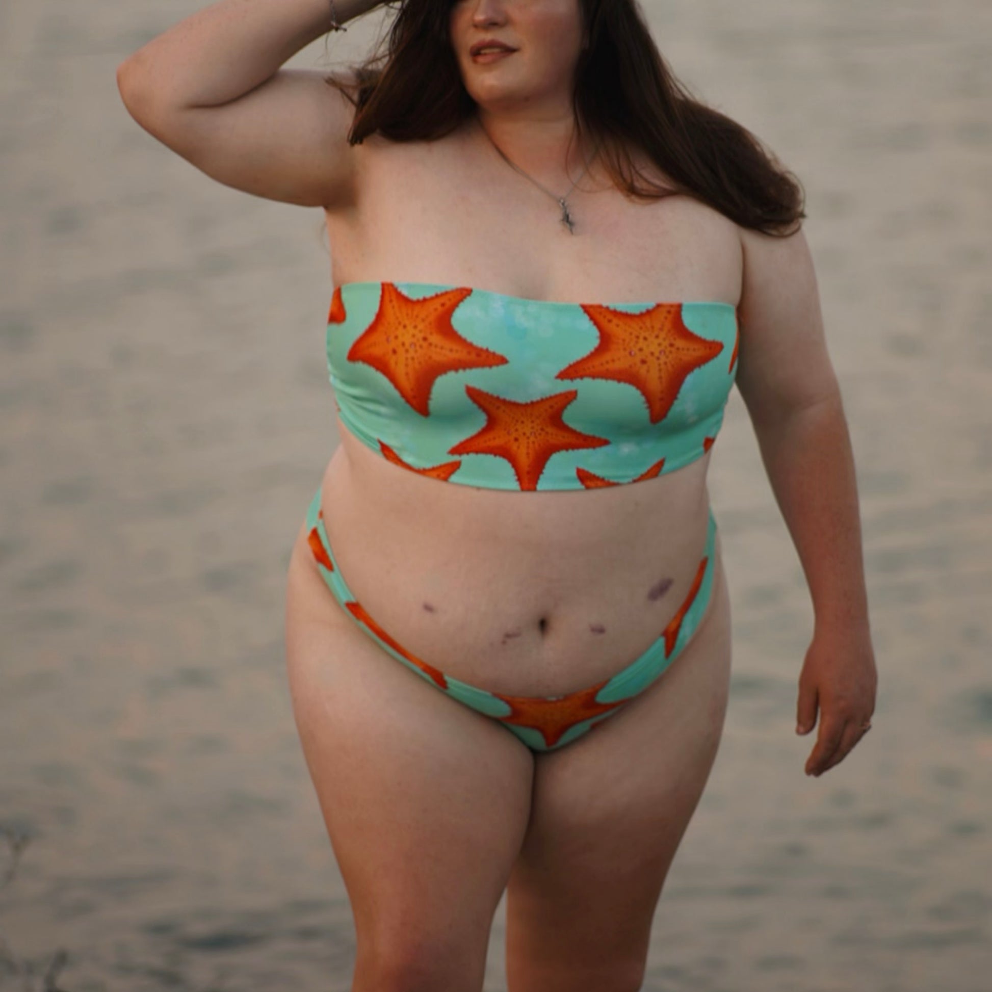 woman standing in water wearing a green/teal and orange starfish bikini