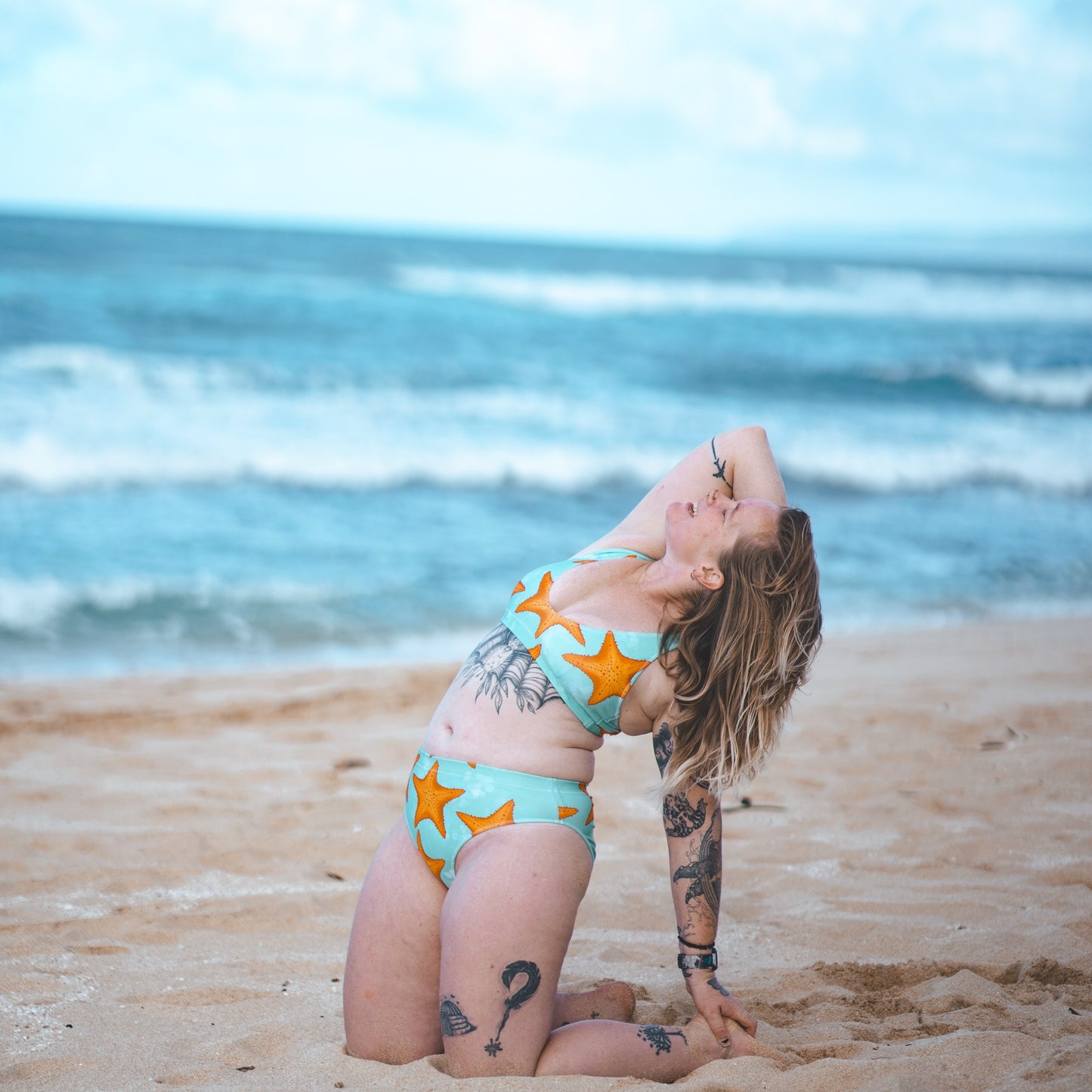 Woman on the beach in a green and orange starfish bikini 