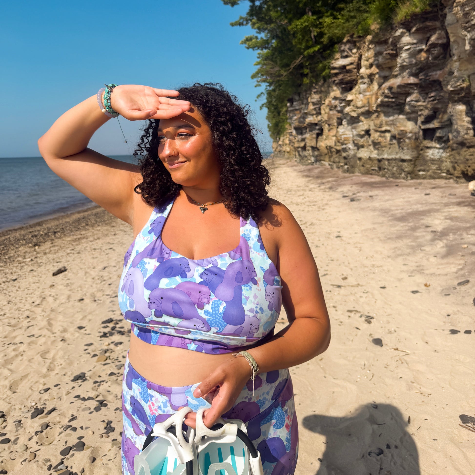 woman standing on a beach with dive gear wearing a purple and blue manatee activewear set