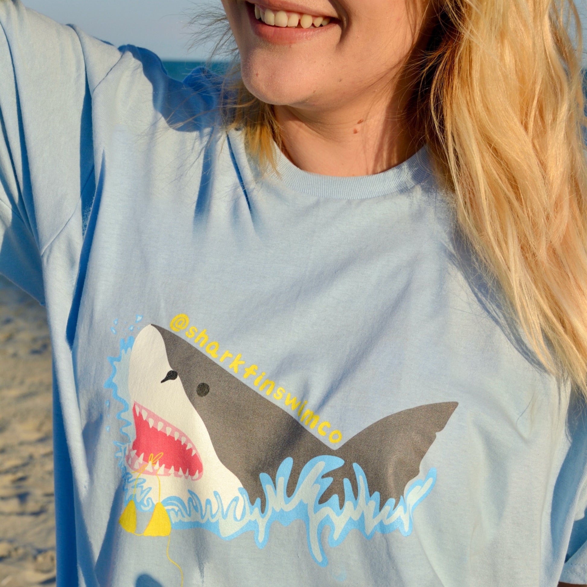 Eco-friendly t shirt with a great white shark and bikini coming out of the ocean 