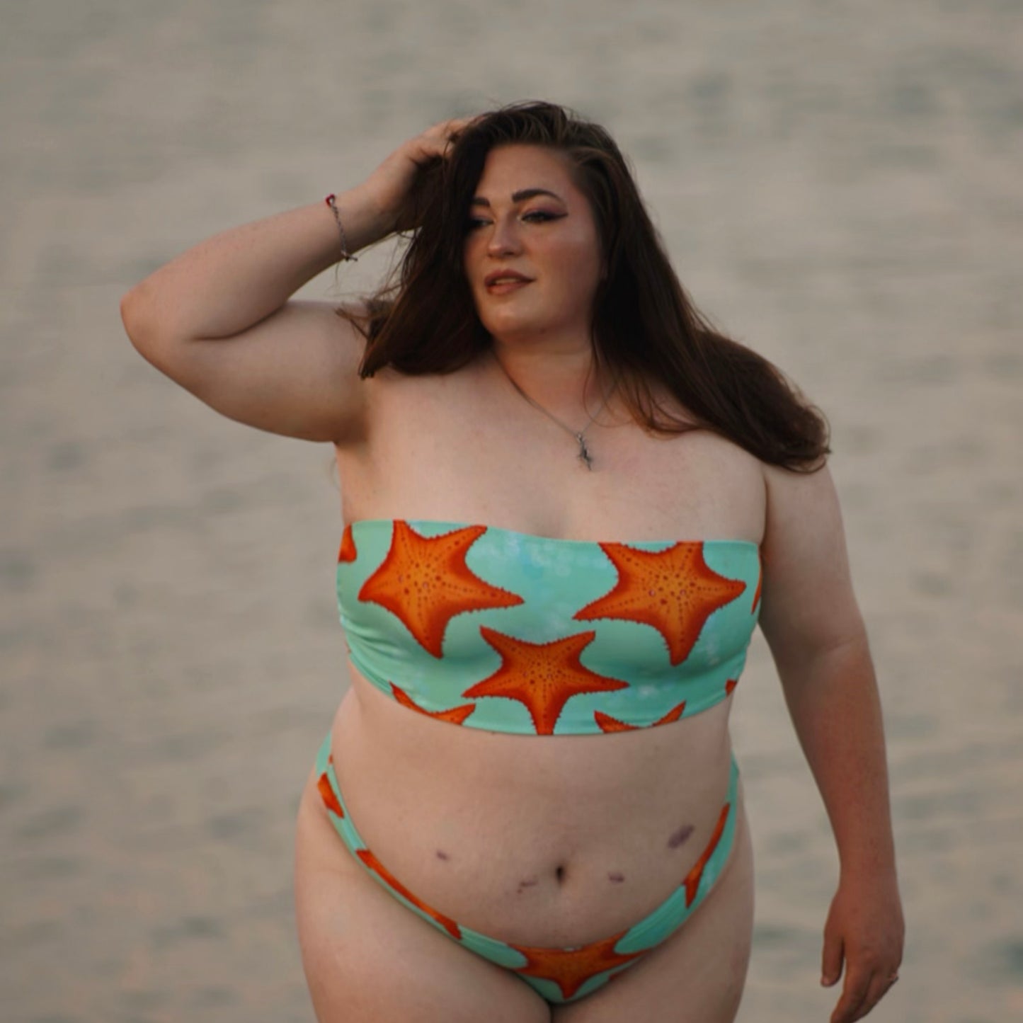 woman standing in water wearing a green/teal and orange starfish bikini